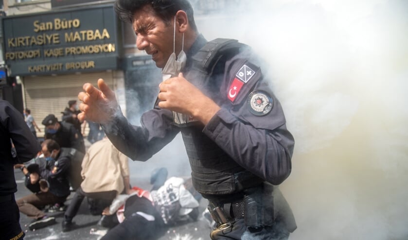 Een Turkse agent staat in een wolk traangas nadat hij zelf per ongeluk de bus had opengemaakt. In de Turkse miljoenenstad Istanbul liepen 1 mei-demonstraties zaterdag uit op confrontaties tussen betogers en politie. Meer dan tweehonderd mensen werden opgepakt. (beeld afp / Bulent Kilic)