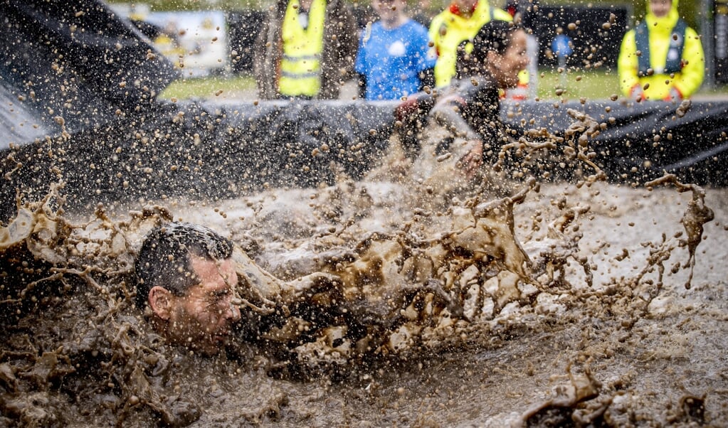 Een deelnemer duikt in ijskoud water tijdens het Fieldlab proefevenement Mud Masters. (beeld anp / Sem van der Wal)