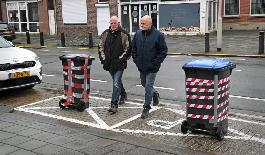 Andy Knobel (l.) en Barro Wijkmans tussen de kliko's tegen wildparkeerders. (beeld Marcel van den Bergh)