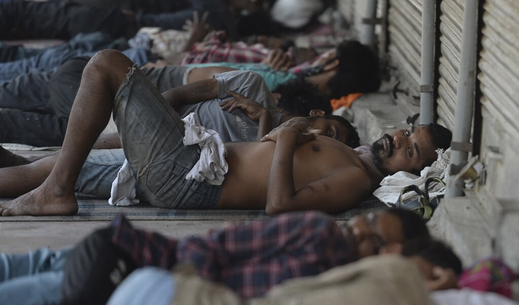 Indiase arbeiders rusten uit voor winkels in New Delhi die door de coronalockdown gesloten zijn. (beeld afp / Arun Sankar)