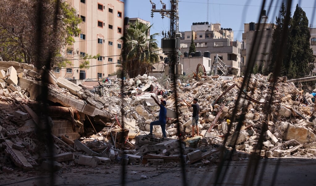 Palestijnse mannen staan naast een gebouw dat de dag ervoor werd vernietigd tijdens Israëlische luchtaanvallen. (beeld afp / Mohammed Abed)