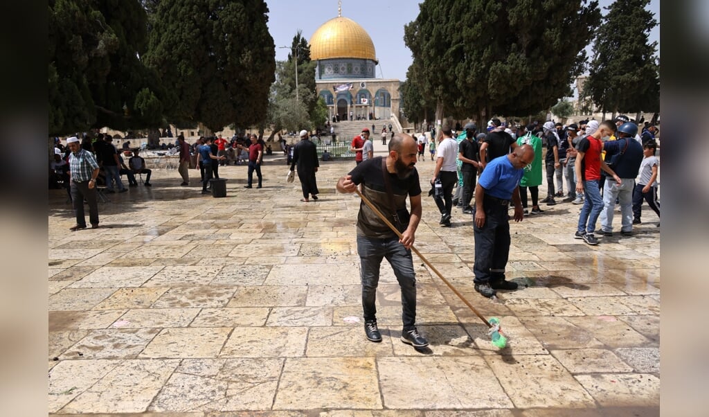 Palestijnen maken het plein voor de Al-Aqsa moskee schoon op maandag 10 mei nadat Palestijnen en de Israëlische politie er opnieuw slaags waren geraakt. Maandag raakten opnieuw 300 mensen gewond tijdens de escalerende conflicten. (beeld afp / Ahmad Gharabli)