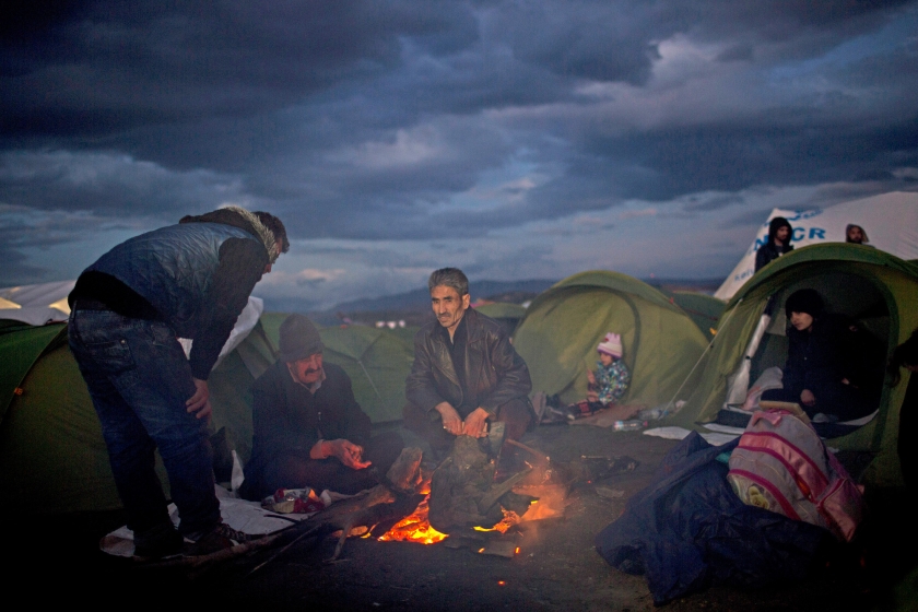 Vluchtelingen uit Irak houden zich bij het Griekse dorp Idomeni warm met een vuurtje, in afwachting tot zij toestemming krijgen de Grieks-Macedonische grens over te steken. (ap / Petros Giannakouris)
