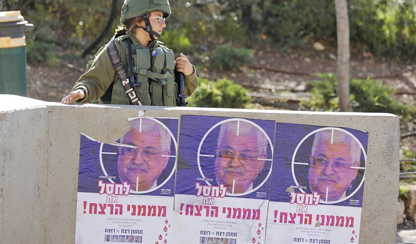 Een Israëlische soldaat naast posters met een foto van president Mahmoud Abbas van de Palestijnse Autoriteit. (afp / Menahem Kahana)