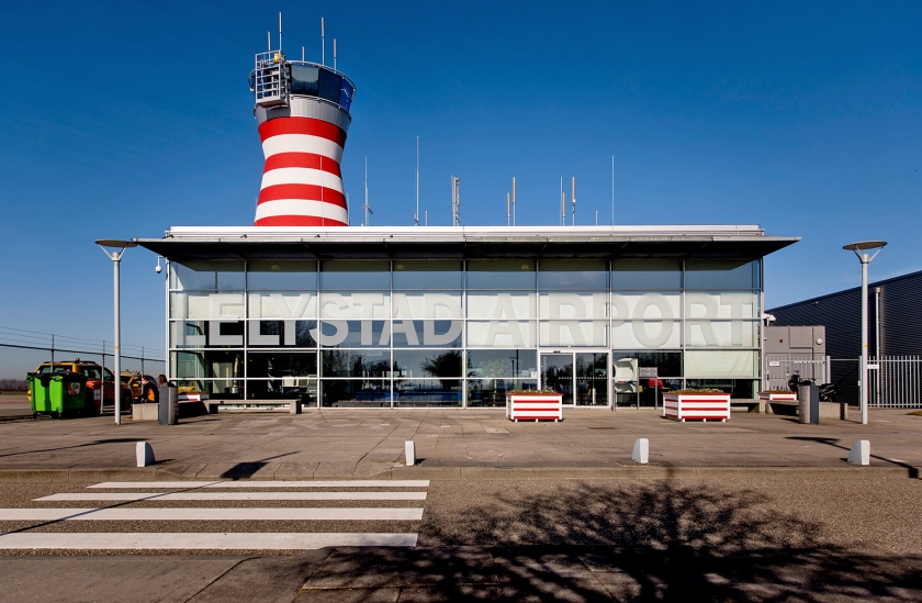 De zon schijnt uitbundig boven de verkeerstoren van Lelystad Airport. Het vliegveld wordt uitgebreid om plaats te bieden aan vluchten naar populaire vakantiegebieden, tot misnoegen van tegenstanders. (anp / Koen van Weel)