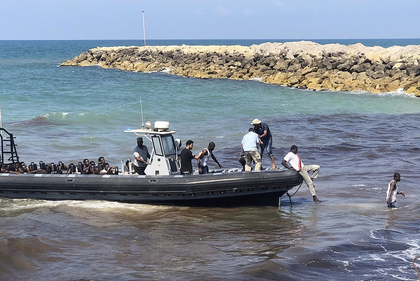 Afrikanen die op de Middellandse Zee van een beschadigde rubberboot zijn gered, worden in Libië aan wal gebracht. (ap / libische kustwacht)
