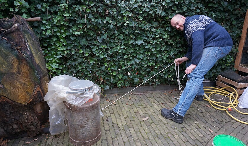 Harm Hol demonstreert hoe hij met een touwtje van een veilige afstand de ontsteking in de carbidbus kan bedienen. (nd)