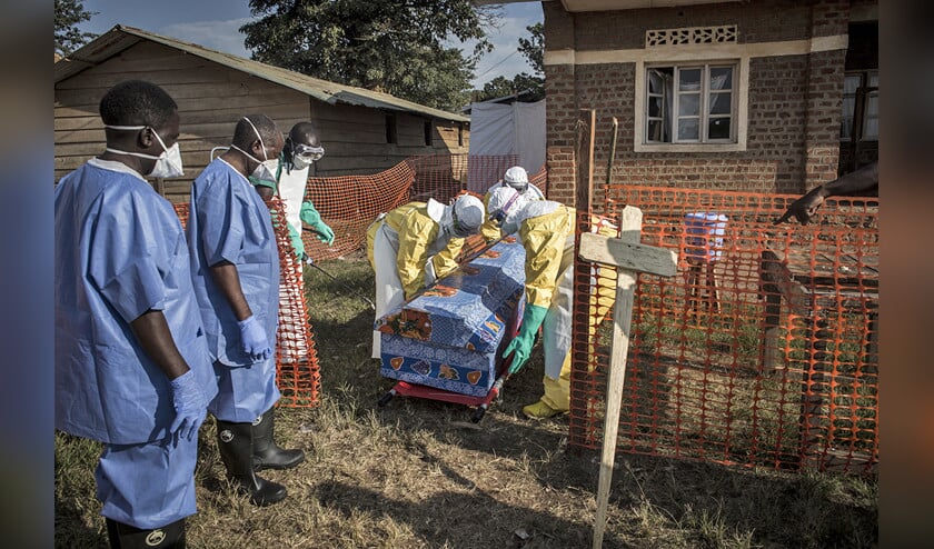 Gezondheidswerkers ontsmetten de kist van een overleden patiënt van wie het vermoeden bestaat dat ebola tot zijn dood heeft geleid. (afp / John Wessels)