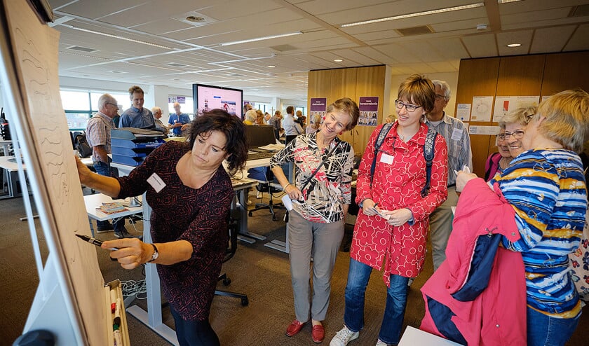Willeke Brouwer trekt bekijks als zij op de redactievloer uitlegt hoe zij te werk gaat als cartooniste van het Nederlands Dagblad. (Jaap Meijer en Sjoerd Mouissie)
