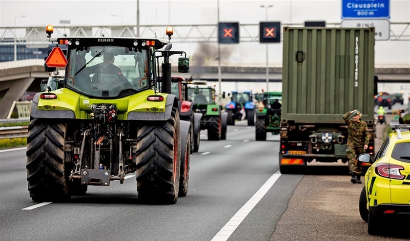 Boeren rijden met hun tractoren door de afsluiting van Defensie heen op de A12 bij Nootdorp. (anp / Sem van der Wal)