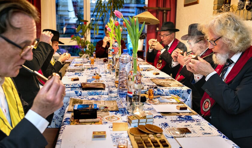 De gildeleden krijgen een minuut de tijd om hun pijp aan te steken. Degene die de pijp het langst brandend houdt, wint de wedstrijd. (Dirk Hol)