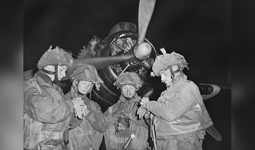 Britse parachutisten zetten de horloges gelijk op maandag 5 juni 1944, 11 uur ’s avonds, vlak voor ze boven Normandië gedropt zullen worden. (imperial war museum / E.G. Malindine en bundesarchiv)