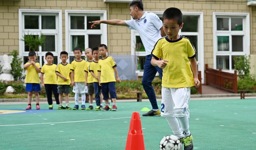 Jongetjes van de Kangcheng-kleuterschool in Shanghai krijgen les in voetbal. De Chinese overheid wil meer investeren in algemene ontwikkeling om de ongezonde prestatiedruk in het onderwijs te verminderen. (afp / Hector Retamal)