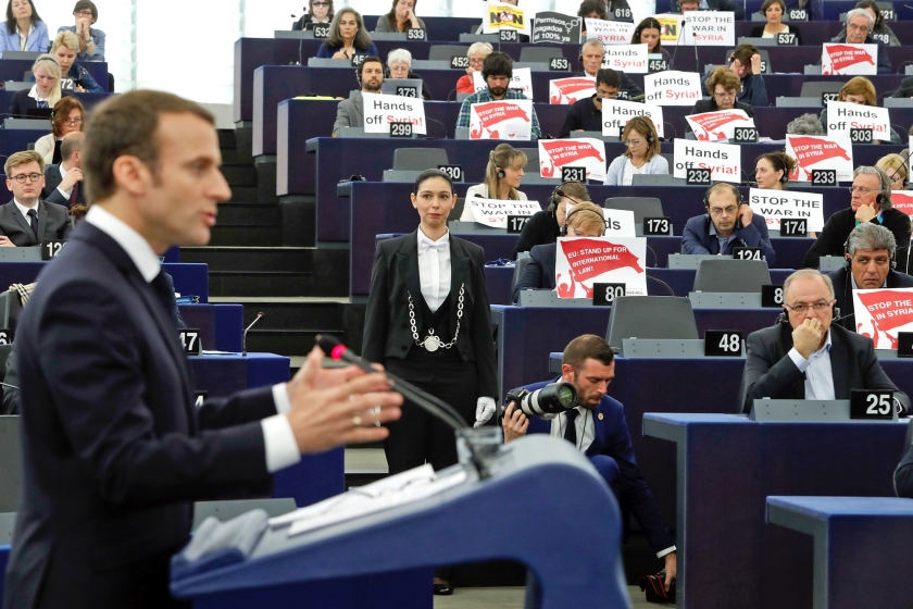 Terwijl Macron spreekt, tonen Europarlementariërs borden met ‘Stop de oorlog in Syrië’, uit protest tegen de recente Amerikaans-Brits-Franse luchtacties. (ap / Jean François Badias)