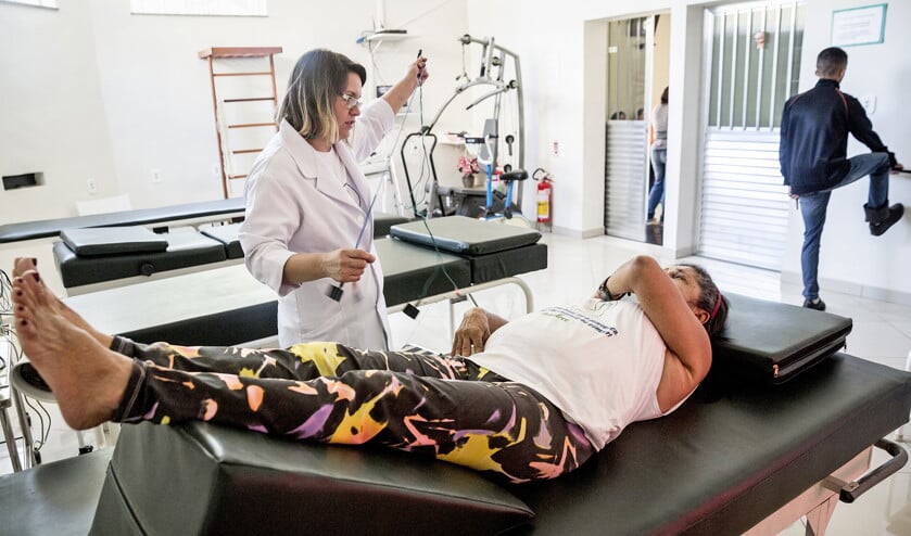 Fysiotherapeute Renata Almeida, vrijwilliger in de door haar collega Mônica Cirne opgerichte kliniek in Rio de Janeiro, helpt een slachtoffer van geweld met oefeningen die herstel moeten bevorderen. (Leonardo Wen)