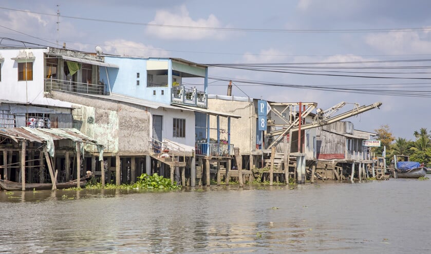 Huizen op palen langs een kanaal in de Mekongdelta. Net als Nederland is Vietnam laaggelegen en moet het zich aanpassen aan de gevolgen van klimaatverandering. (istock)