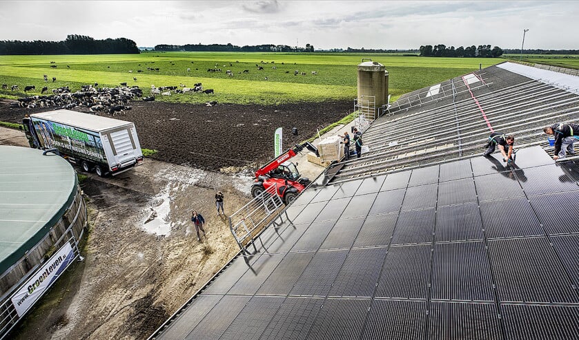 Op het dak van een koeienstal in het Friese Oldetrijne worden zonnepanelen geplaatst. (Raymond Rutting)