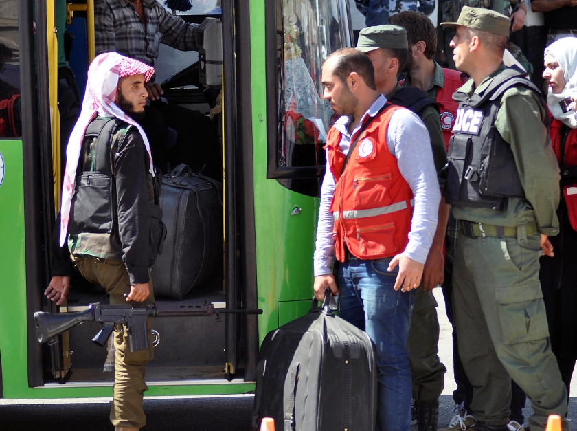 Niet alleen bewoners worden per bus uit heroverde wijken gereden, ook militairen van Assad stappen in om na de overwinning verder te trekken. (ap)