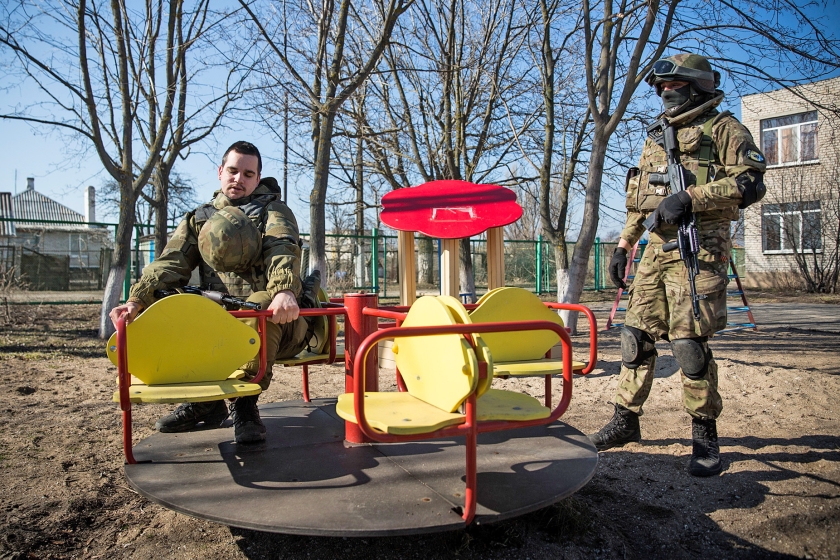 Oekraïense militairen bij een speeltoestel van een schoolgebouw in Lebedynske dat dienst doet als kazerne. (getty images / Andrew Burton)