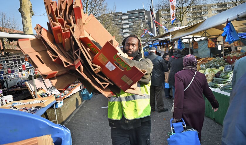 Bernardo Bailey, bewoner van de Rotterdamse Afrikaanderwijk, ruimt dozen op bij de Afrikaandermarkt. Buurtbewoners hebben het opruimen overgenomen van de gemeente. Dat houdt de markt ook gedurende de dag schoon en zo hebben mensen die anders thuiszitten iets omhanden. (Marcel van den Berg)