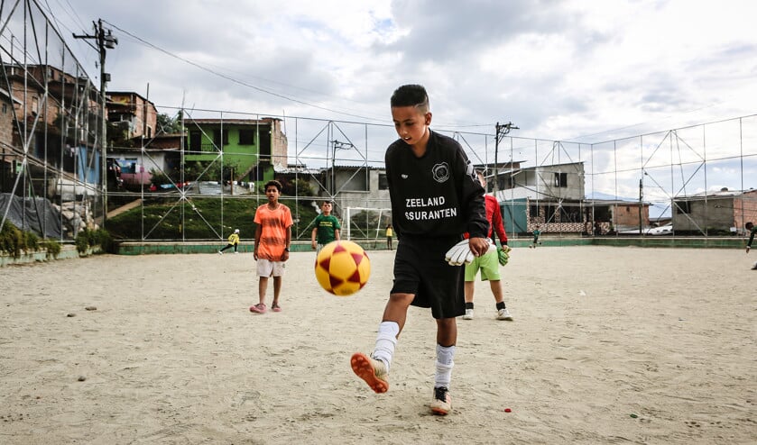 Het hooggelegen voetbalveld voor straatkinderen in de Colombiaanse stad Medellín is nu nog een zanderige boel, waar iedereen door elkaar loopt. (Maarten Boersema)