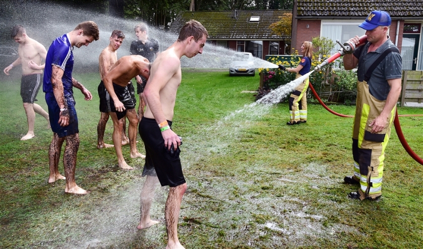 De brandweer spuit deelnemers schoon na afloop van het Nederlands kampioenschap zwientie tikken, vorige maand in Luttenberg. (Marcel van den Bergh)