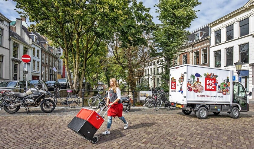 Een medewerker van onlinesupermarkt Picnic bezorgt boodschappen in Utrecht. De voertuigen van Picnic zijn al elektrisch. (Raymond Rutting)