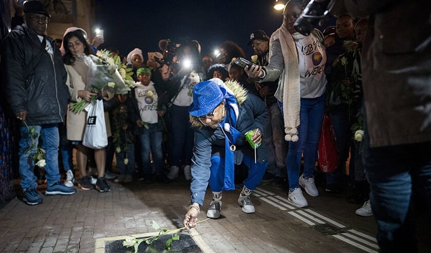 De moeder van rapper Bolle legt bloemen bij de gedenksteen van haar zoon tijdens de herdenking donderdagavond in Amsterdam-Zuidoost. (Freek van den Bergh)