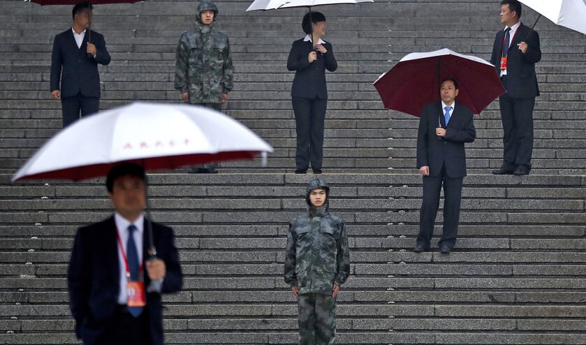 Beveiligingsambtenaren houden paraplu’s omhoog op de trappen bij de Grote Volkszaal in Peking. Ze wachten in de regen tot de afgevaardigden aankomen voor de openingsceremonie van het 19e congres van de Communistische Partij (ap / Andy Wong)
