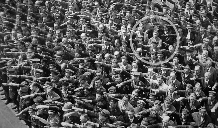 De massa in Hamburg salueert en brengt de Hitlergroet. Landmesser weigert en slaat de armen over elkaar. (wikimedia)