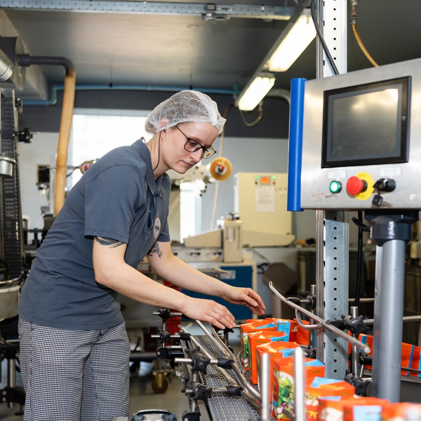 Een medewerker van matzesfabriek Hollandia in Enschede bij de typerende oranje matzesdoosjes. (Katja Poelwijk)