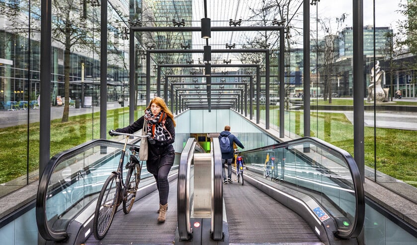 Fietsers komen en gaan bij een ondergrondse stalling naast station Amsterdam Zuid. (Raymond Rutting)