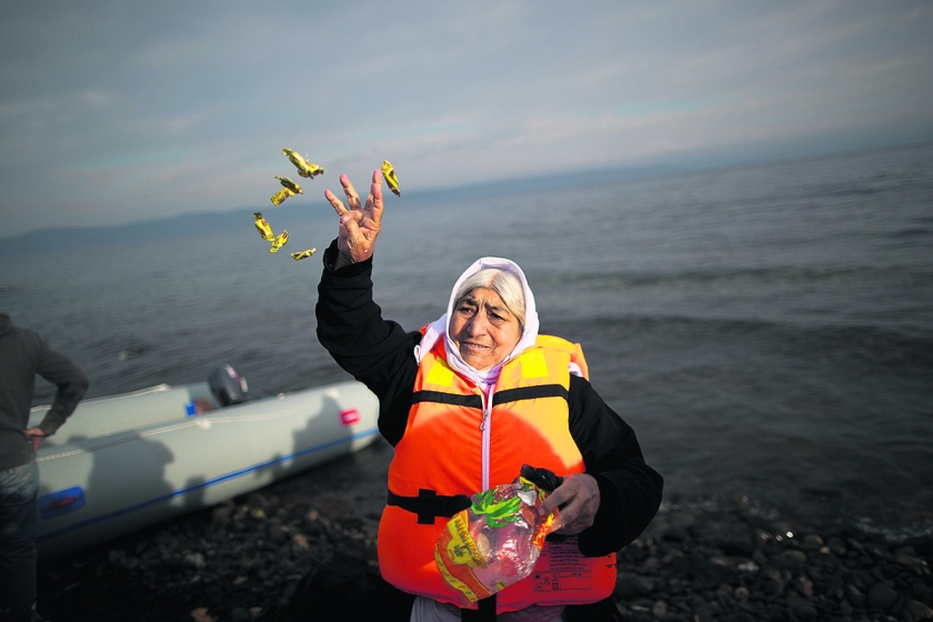 Een vluchteling strooit met snoepjes bij aankomst op het Griekse eiland Lesbos. (ap / Muhammed Muheisen)