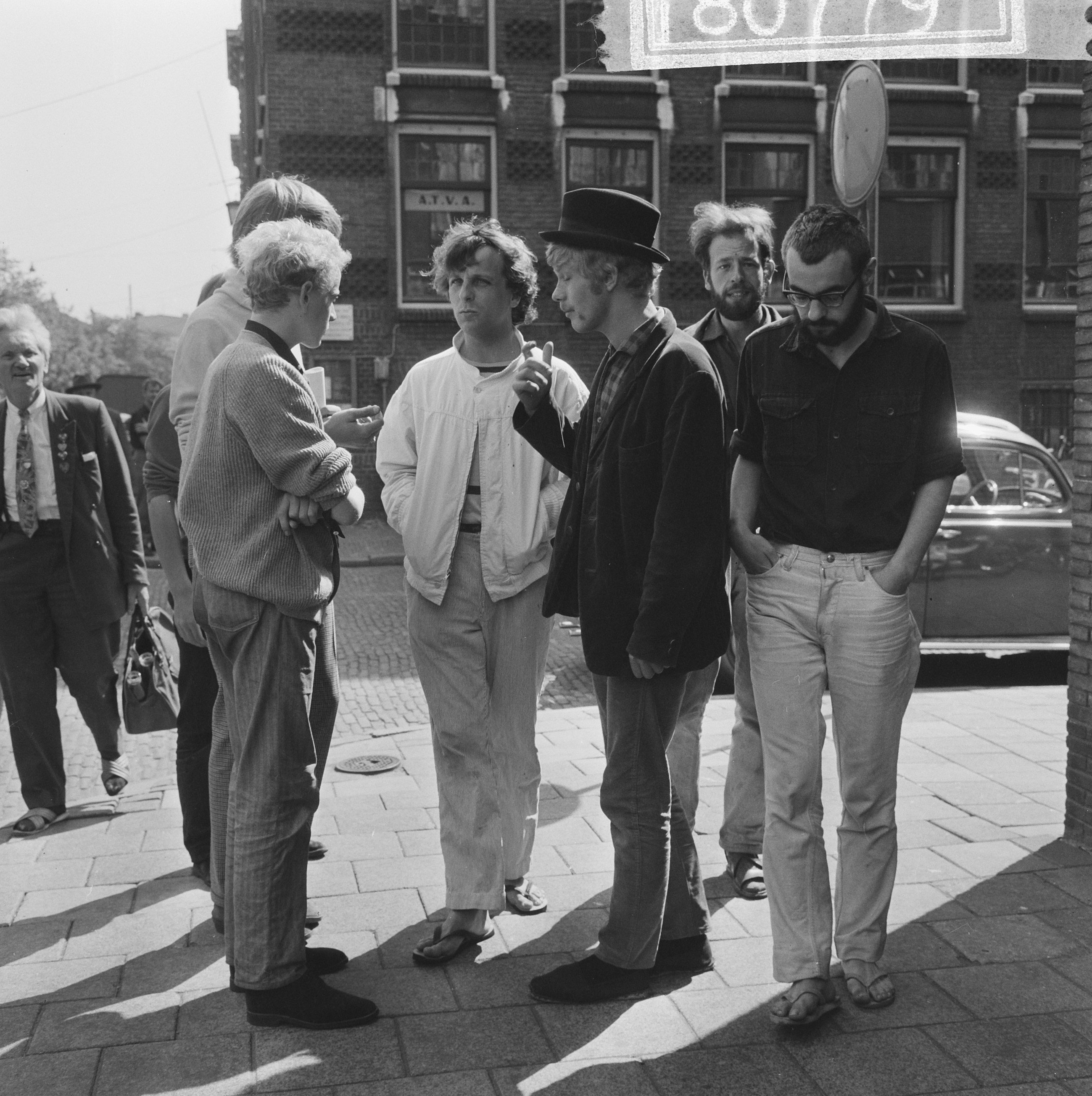 Drie vooraanstaande provo’s in Amsterdam, 1965: Robert Jasper Grootveld (in witte jas), Rob Stolk (met hoed) en Roel van Duyn (rechts).