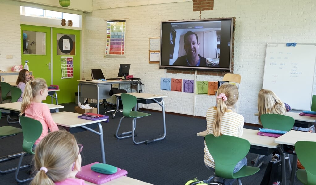 Leerkracht Jeroen Elzinga geeft via een digitale verbinding les aan de leerlingen uit groep 4. Christelijke basisschool Futura is deze week weer gestart met klassikaal onderwijs nadat dit vanwege de coronamaatregelen wekenlang niet mogelijk is geweest. (beeld Dick Vos)